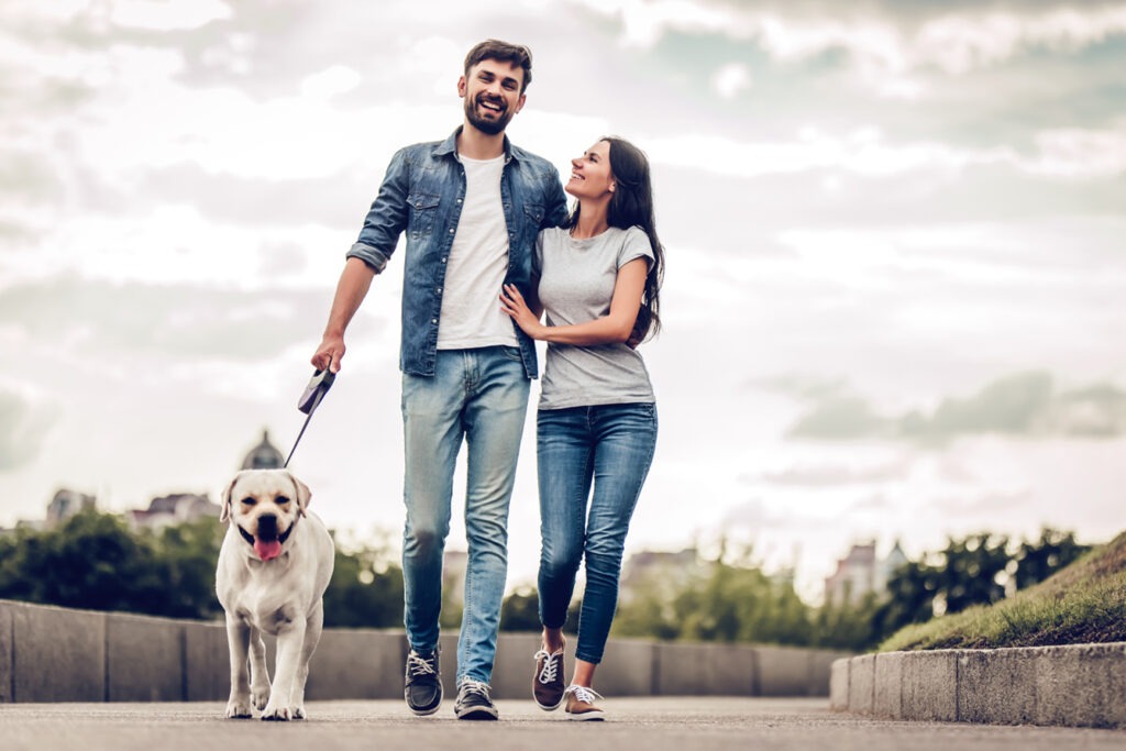 Young couple enjoying walking their dog